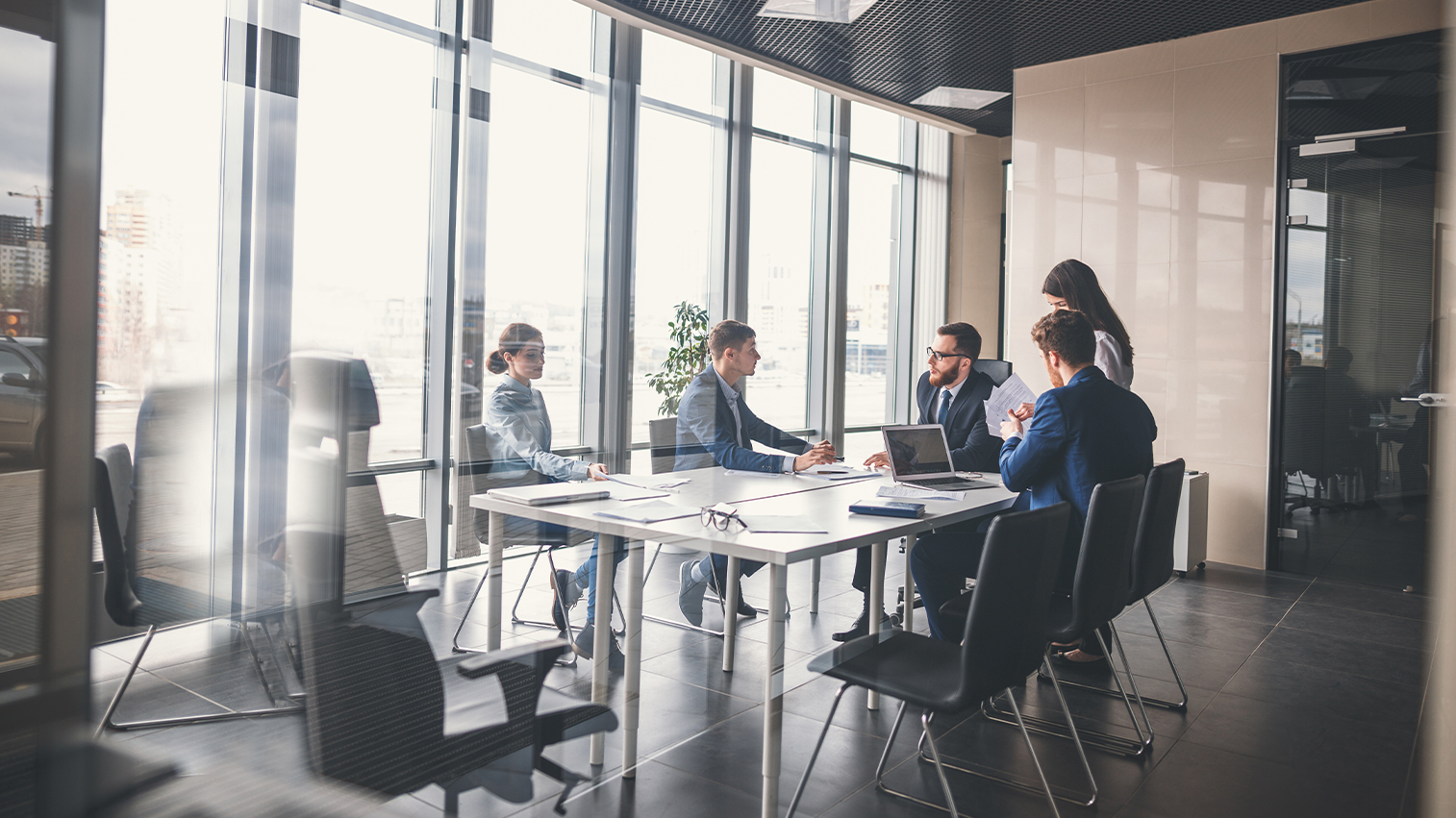 A view through the glass of a conference room of an ongoing meeting in a modern space.
